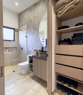 Bano privado con vestier integrado, ducha en vidrio y muebles modernos.
