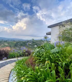Sendero exterior con jardines ornamentales y vista panoramica en casa campestre en venta.
