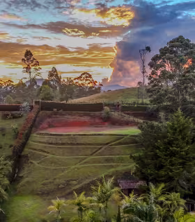 Vista aérea del lote campestre en El Carmen de Viboral, con terreno verde aterrazado y cielo de atardecer.