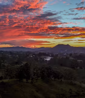 Vista panorámica del valle y las montañas de El Carmen de Viboral durante un atardecer rojo y naranja.