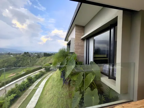 Balcon de casa campestre con vista panoramica a montanas y zona verde.