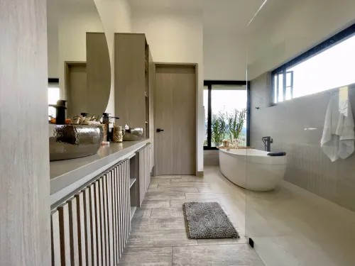 Bano principal moderno con tina independiente, doble lavamanos y acabados de lujo.