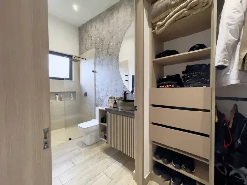 Bano privado con vestier integrado, ducha en vidrio y muebles modernos.