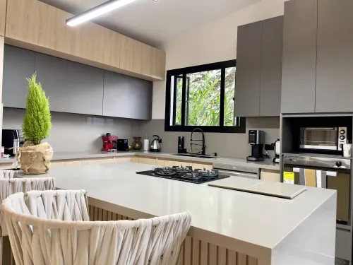 Cocina con isla, estufa empotrada y acabados modernos en casa campestre de lujo.