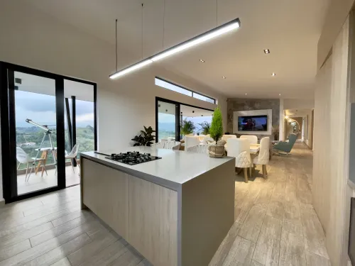 Cocina con isla central y salida a terraza con vista campestre.