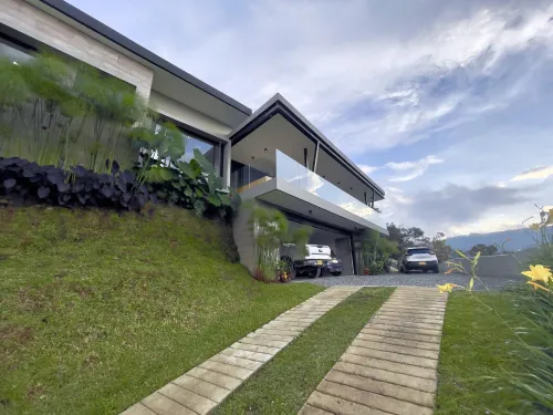 Fachada moderna de casa campestre en venta con via de acceso y zona verde.