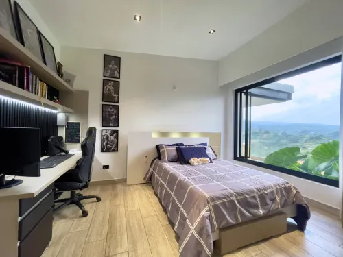 Habitacion auxiliar con escritorio de trabajo, cama y vista panoramica exterior.