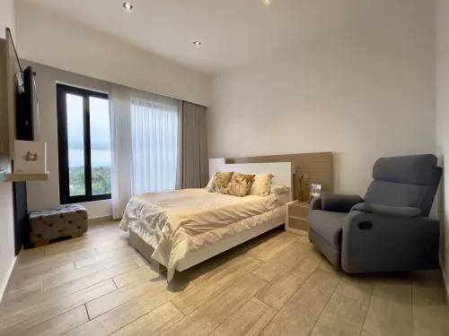 Habitacion auxiliar con ventanal grande, cama doble y sillon reclinable.