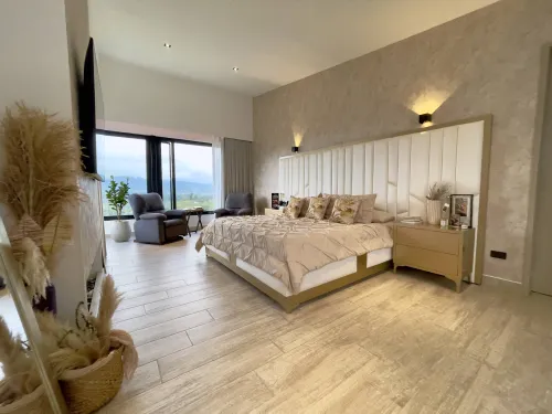 Habitacion principal amplia con cama king, sala auxiliar y vista panoramica campestre.