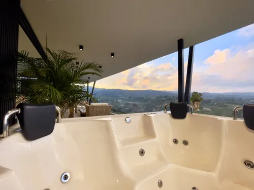 Jacuzzi con vista al atardecer y paisaje montanoso en casa campestre de lujo.