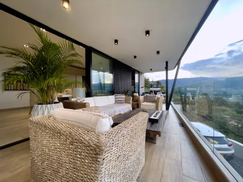 Sala exterior en terraza cubierta con vista panoramica al paisaje campestre.